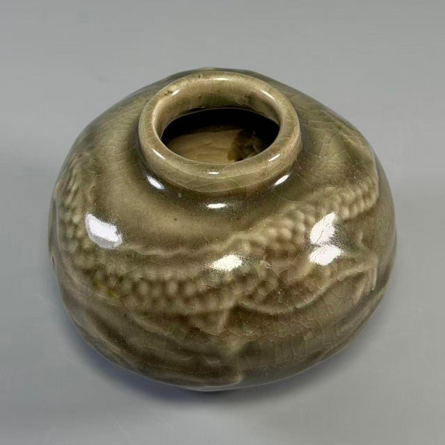 Hand-thrown Longquan celadon porcelain with a rich olive-green glaze, raised dragon and cloud relief motifs on the body....