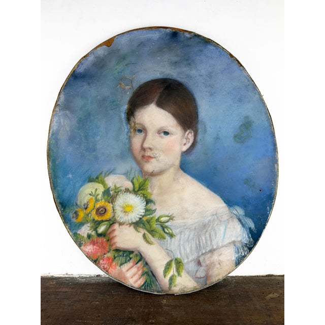 Beautiful 19th century pastel portrait depicting a young girl holding a bouquet of flowers, set against a luminous blue...