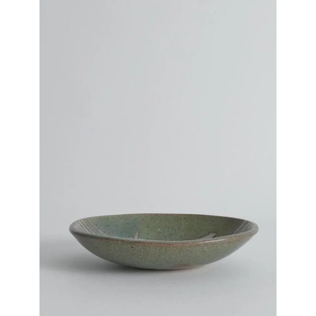 This Mid-Century Modern handmade stoneware bowl from the 1960s exemplifies the organic craftsmanship and artistic...