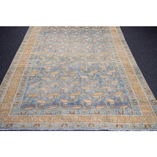 The field panel-abrashes from slate to light blue to powder, and displays a row by row pattern of angular boteh leaves and...