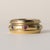 An iconic vintage Piaget Possession spinner ring in 18K yellow gold, featuring a rotating band set with emeralds, rubies,...
