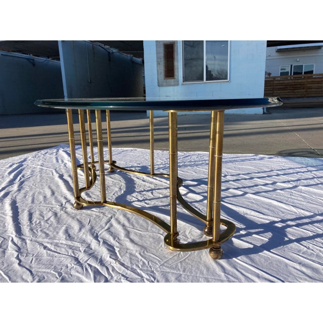 Vintage solid brass base glass top “racetrack” coffee table in faux bamboo. This table retains its original freeform heavy...