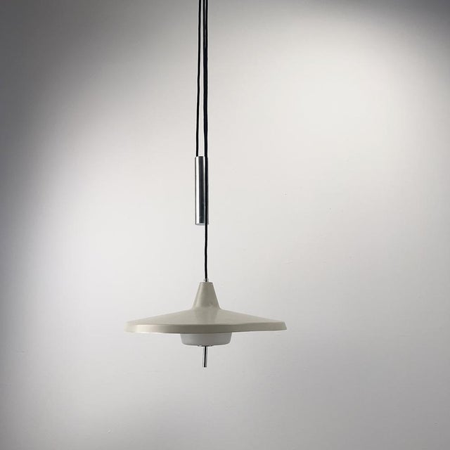 Elegant pendant light made of grey lacquered aluminum sheet with an opal glass diffuser. The light's height can be...