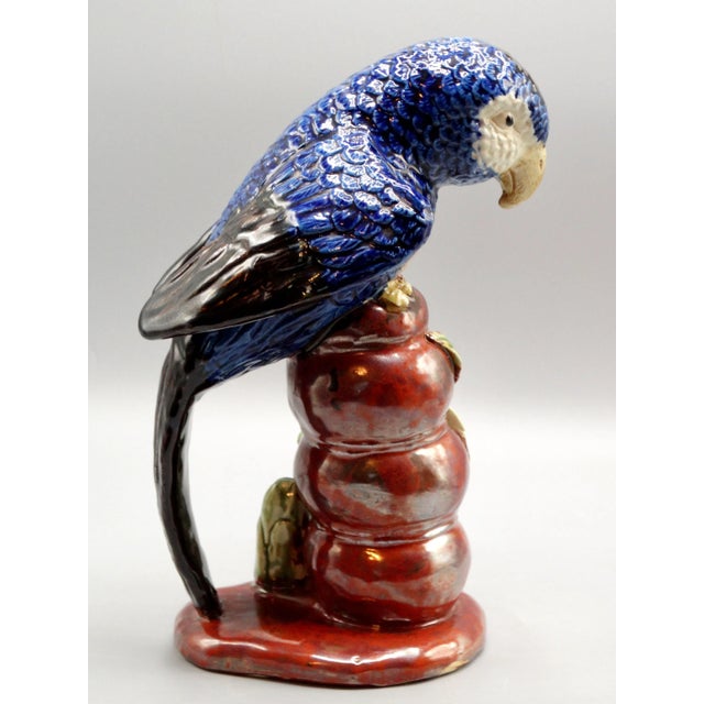 A circa 1960's Italian glazed majolica parrot hand painted in brilliant shades of blue perched upon a rock and bamboo...
