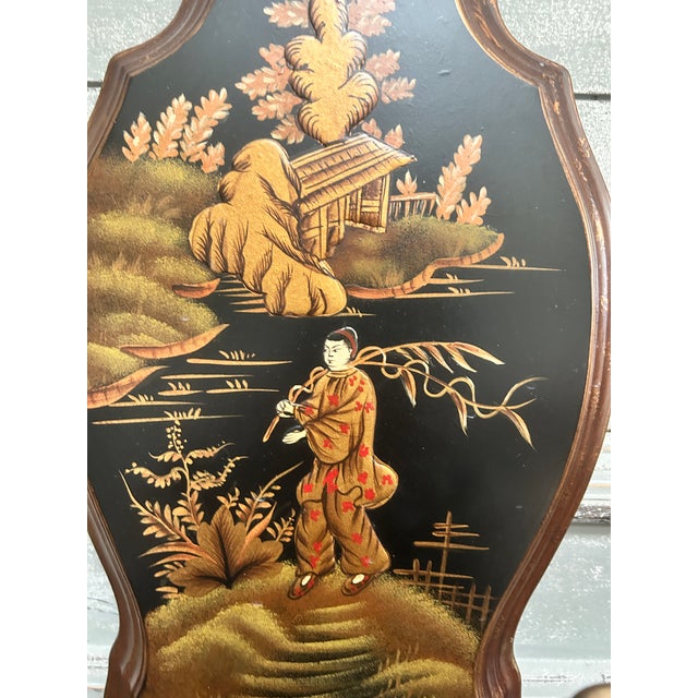 A decorative pair of Chinoiserie-style wall sconces featuring hand-painted scenic panels depicting figures in a stylized...