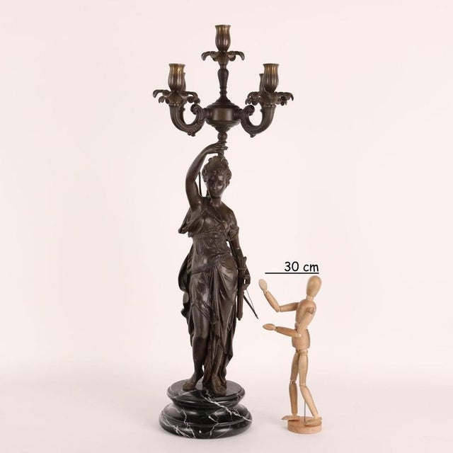 Bronze candelabra with five flames. On a circular base in black marble rests a bronze statue depicting Diana the Huntress...