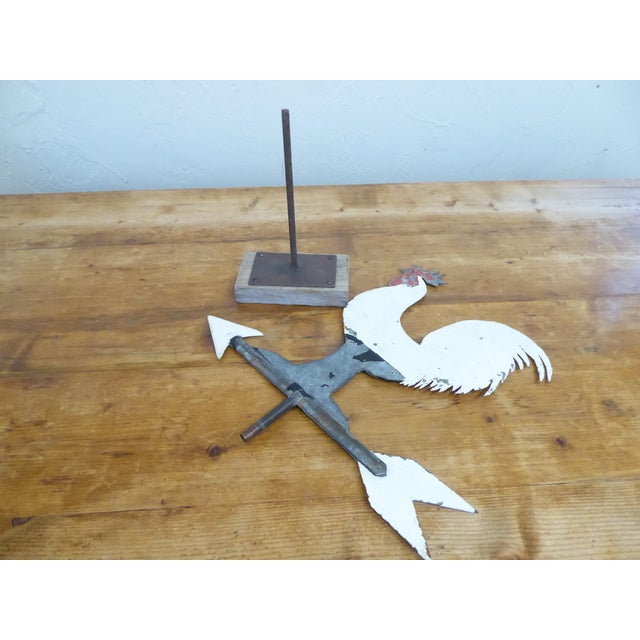 This antique rooster weathervane is mounted on a iron and wooden stand and has weathered, original paint.