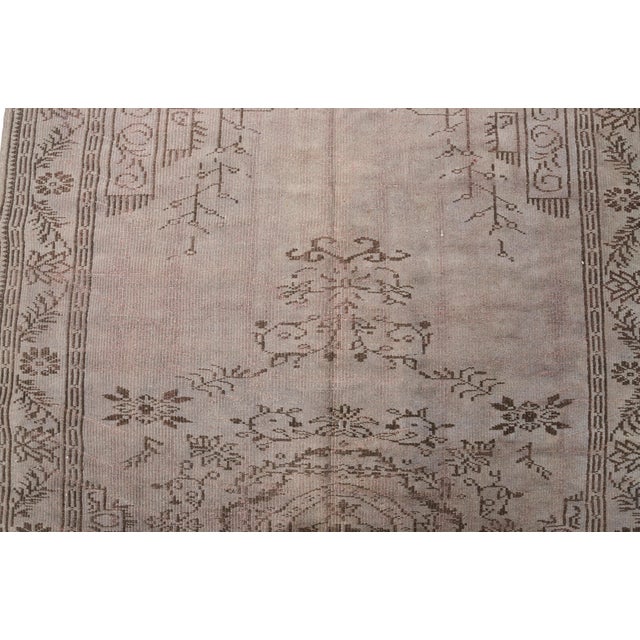 This is a vintage Turkish Oushak rug from the Mid 20th Century. The piece was hand-knotted.