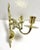 A decorative pair of vintage brass wall candle sconces with graceful scrolling arms, pierced scrollwork, and two taper...