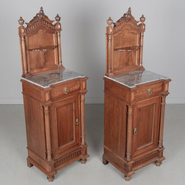 A pair of tall Italian Renaissance Revival marble top nightstands made of solid walnut with architectural details...