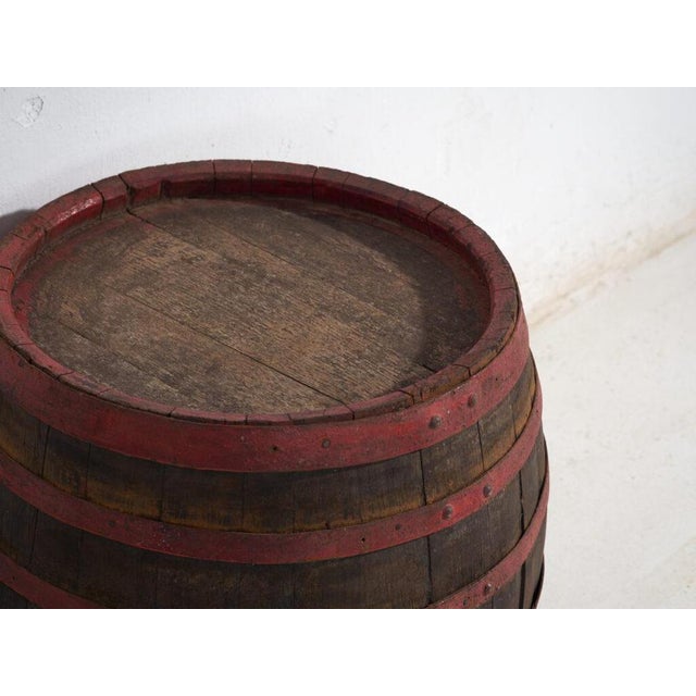 This antique wooden barrel with iron hoops features a wide cylindrical body of oak staves held by hand-forged iron hoops...