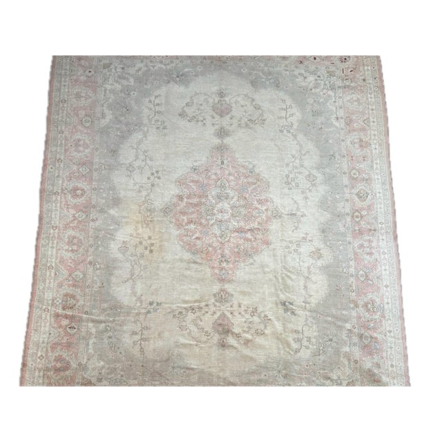 This early 20th century Turkish Borloo rug features a softly faded ivory field anchored by a delicate blush pink central...
