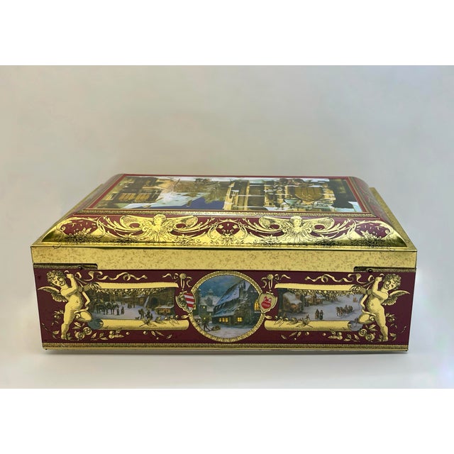 An elaborate lidded storage box edged with scrollwork and cherubs featuring panels illustrated with old fashioned winter...