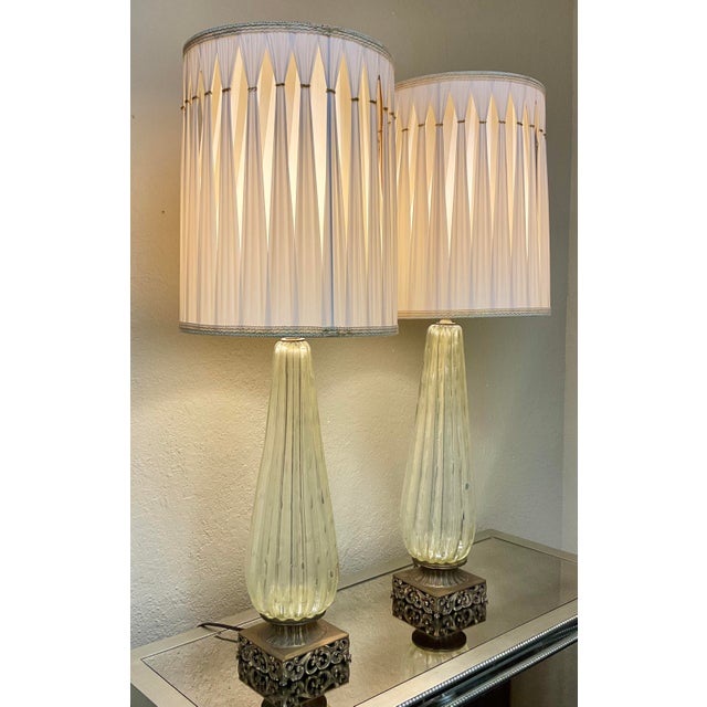 This pair of elegant mid-century Murano glass table lamps features a ribbed, teardrop-shaped hand-blown glass body resting...