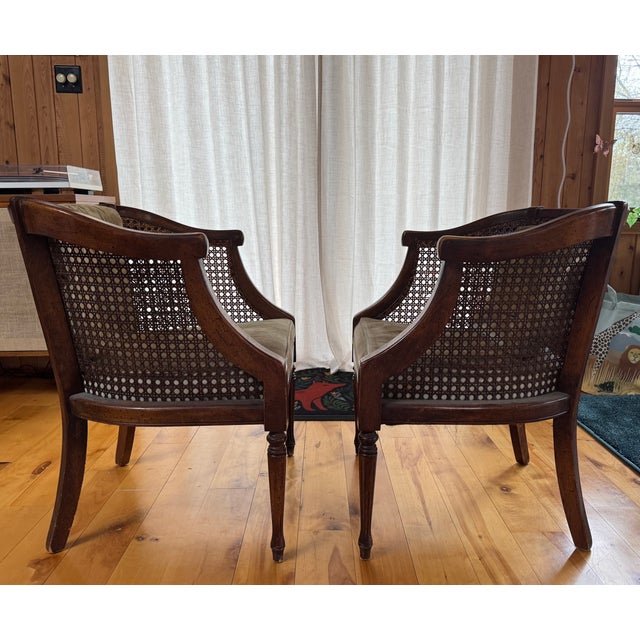 A beautifully crafted pair of vintage cane-back barrel armchairs in a classic French Regency / Hollywood Regency style,...