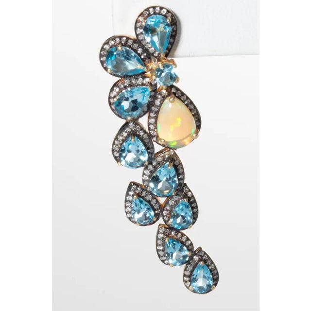 A fabulous pair of faceted, pear-shaped blue topaz gemstones bordered in pave`-set diamonds and featuring one pear-shaped...