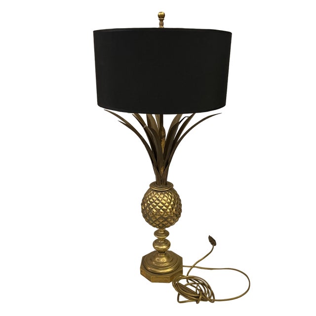 Hollywood Regency style table lamp. Gold pineapple-shaped base with delicate gold leaves. Octagonal base and black shade....