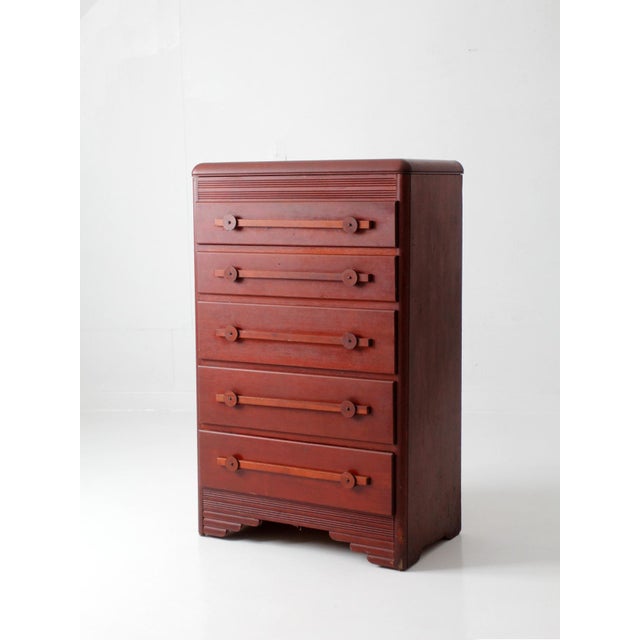 A handsome early 20th-century Art Deco dresser featuring a warm reddish-brown finish, a rounded waterfall top, and elegant...