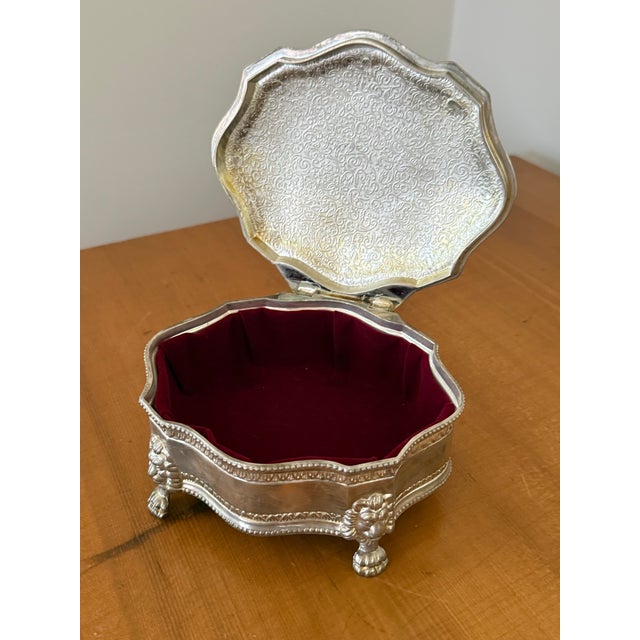 Vintage silverplate hinged trinket box with an engraved crest of a lion rampant and four lion paw feet. Octagonal lobed...