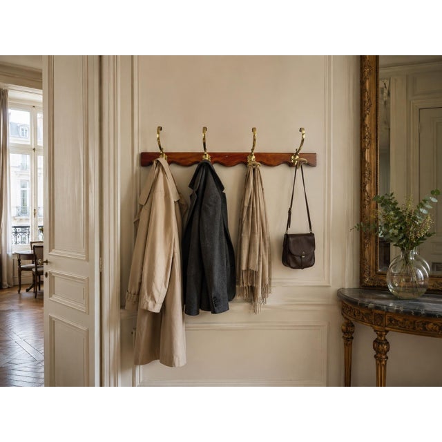 Antique wall-mounted coat rack in wood and brass, dating from the 1900s. It consists of an elegant molded wooden frame,...