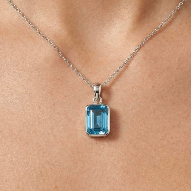 This refined pendant showcases the striking beauty of a Blue Topaz gemstone, celebrated for its vivid ocean-blue hue and...