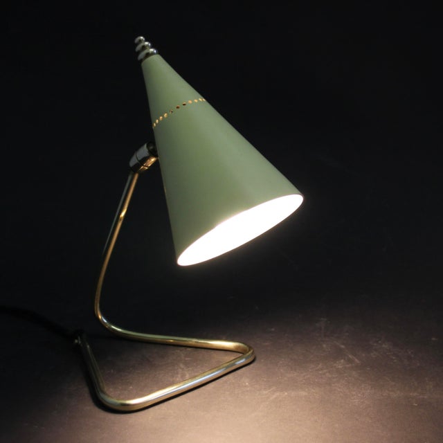 This vintage (desk) table lamp in the Guariche style with solid brass parts and the original soft yellow painted aluminum...