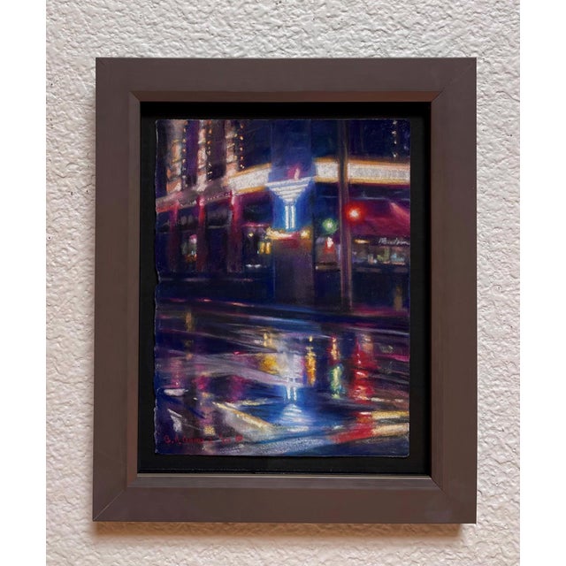 This pastel artwork captures a vibrant urban night scene, where the interplay of light and reflection creates a dynamic...