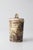 A striking vintage studio pottery jar featuring deeply carved decoration, an earthy palette, and an arched handle rising...