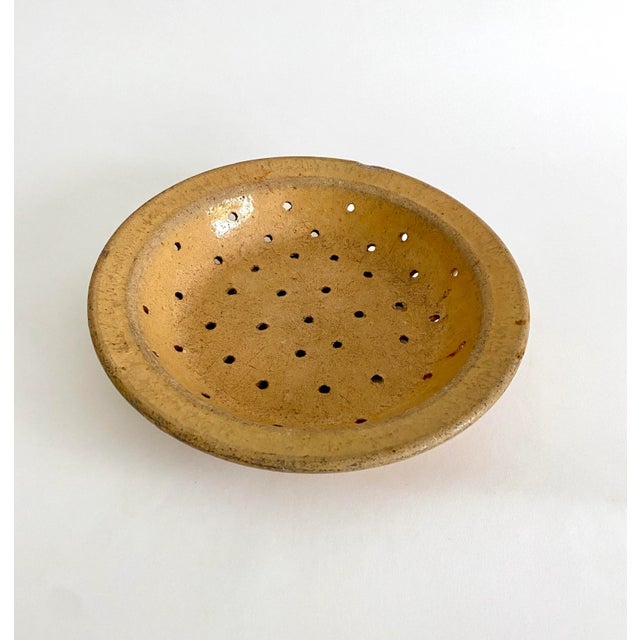 Early 20th century antique French terracotta fruit strainer with a mustard glaze rests on three small feet. From southern...