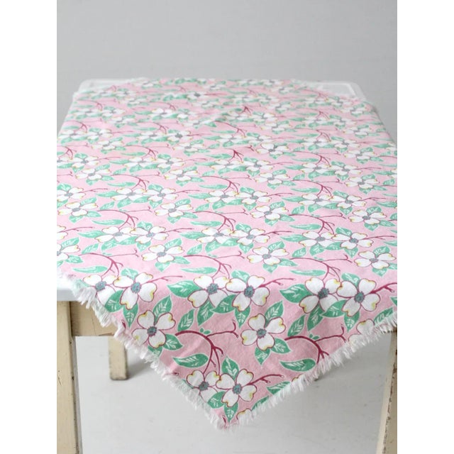This is a vintage pink floral tablecloth. The square cotton table covering features a soft pink background with a white,...