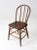 An antique farmhouse Windsor dining chair featuring a painted wooden frame, gracefully bowed back, and traditional turned...