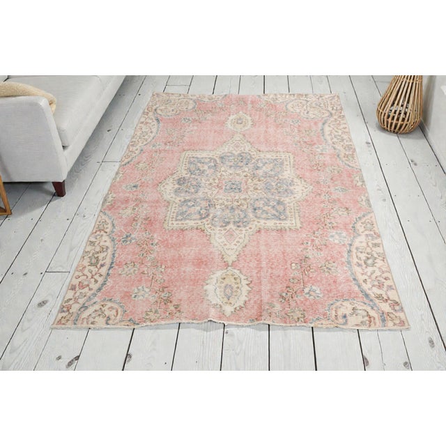 This is a vintage Turkish Oushak rug from the Mid 20th Century. The piece was hand-knotted.