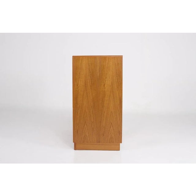 Scandinavian teak sideboard on a plinth, featuring six drawers on the left and a compartment with a door on the right....