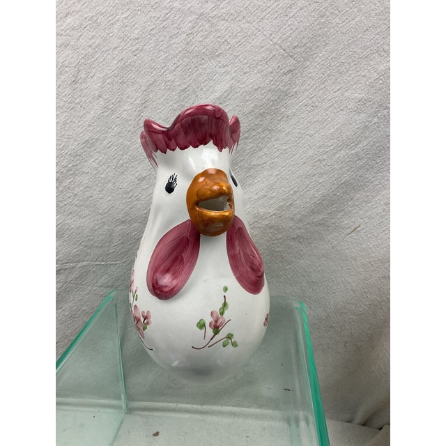 Whimsical hand painted ceramic pitcher in a chicken shape. The sides and front of the body have floral paintings. Signed...