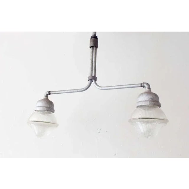 An Industrial dual light fixture of steel and robust Holophane glass.