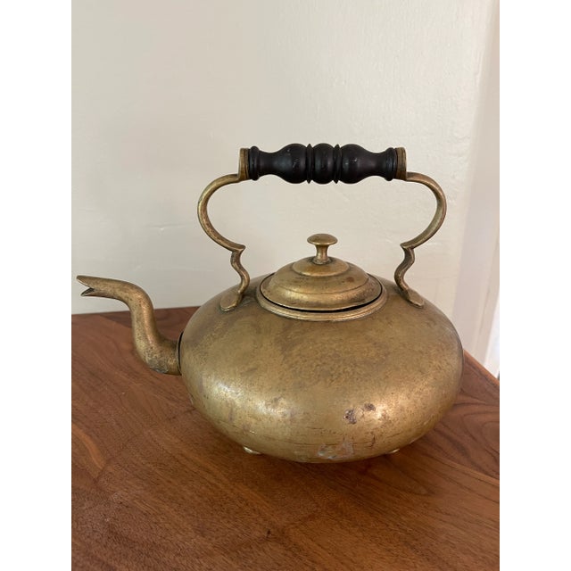 Beautiful antique brass kettle with wooden handle and four feet.
