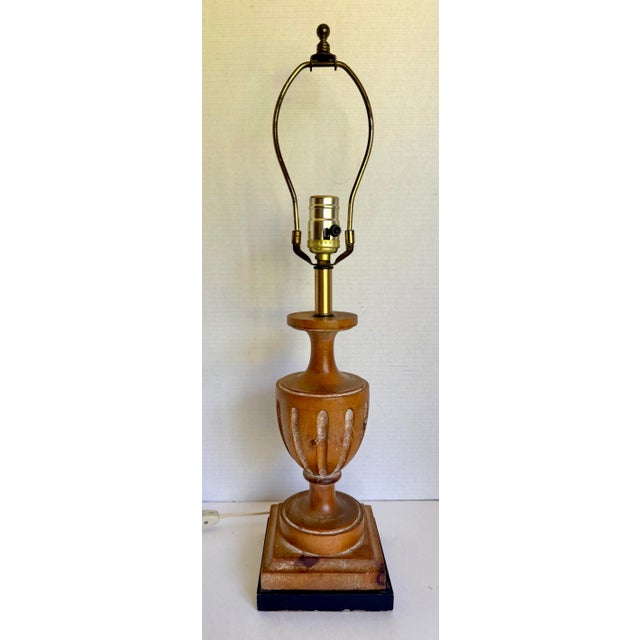 A charming vintage Neoclassical-style table lamp, featuring a sculptural carved wood urn with a warm honey-brown finish...
