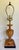 A charming vintage Neoclassical-style table lamp, featuring a sculptural carved wood urn with a warm honey-brown finish...