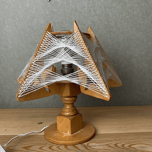 Vintage wooden sculptural table lamp with string-art geometric detailing. The combination of wood panels and white thread...