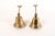 A pair of brass wall-mounted bells with a flared, stepped bell body and a long hinged bracket ending in a forked, two-hole...