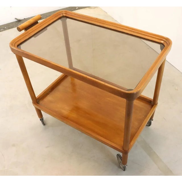 Beautiful, very beautifully designed bar cart made of warm-colored wood with handy wheels and a beautiful smoked glass...