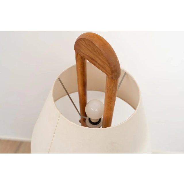 Floor light by +LYS Denmark. The light has an arced wooden frame and base. This piece comes with a beige/white fabric...