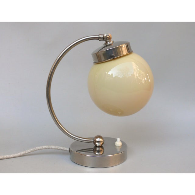 A bedside lamp in the austere Bauhaus style, made in Germany in the 1920s/30s. The lampshade, made of beige cased glass,...