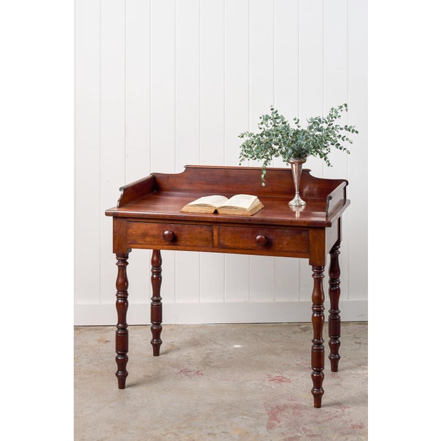 This 19th-century two-drawer mahogany desk/wash stand features a gallery back with curved edges that frame the back and...