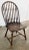 Antique handmade Windsor style chair featuring rounded spool back, curved seat, and four turned wood legs attached by...