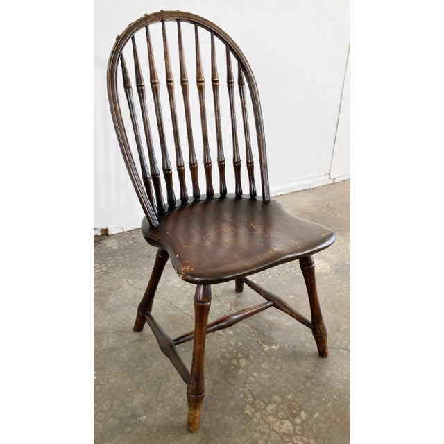Antique handmade Windsor style chair featuring rounded spool back, curved seat, and four turned wood legs attached by...