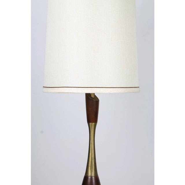 A organic-form Tony Paul table lamp of turned walnut and brass elements, with tall cylindrical off-white shade.
