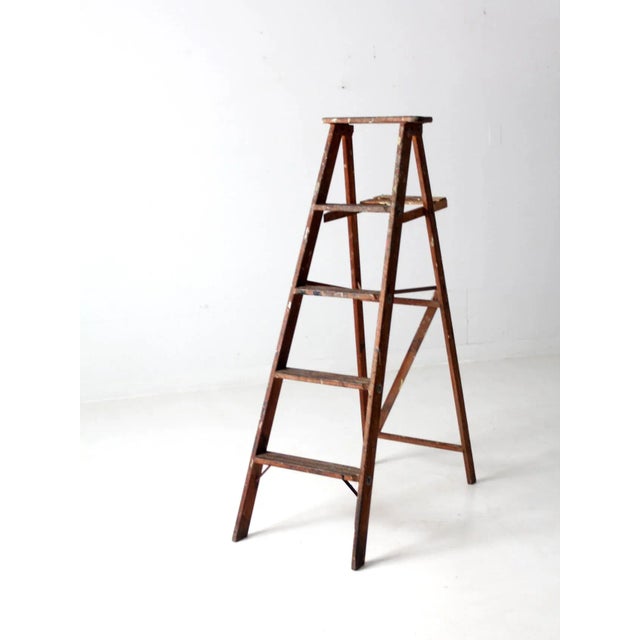 This is a vintage wooden painter's ladder. The a-frame ladder features four rung steps, a back shelf, and a cross back...