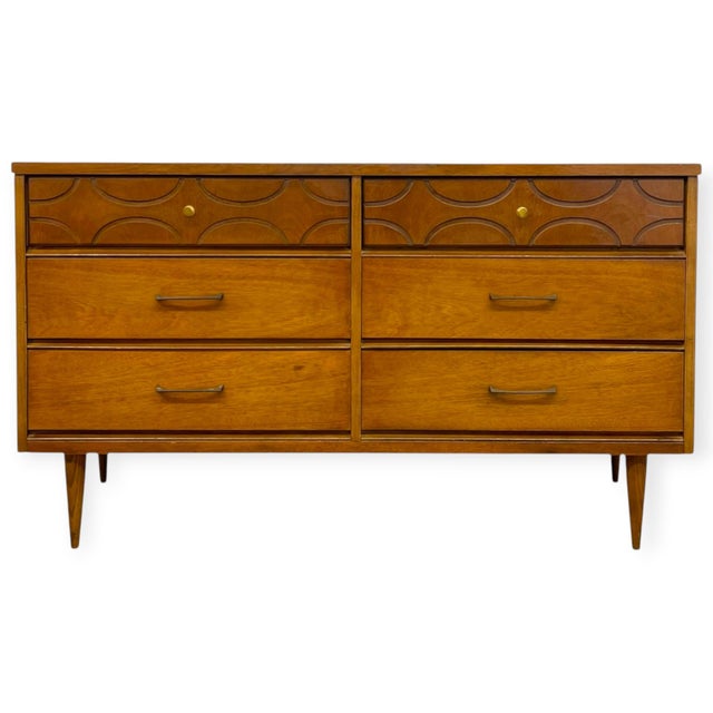 Crafted by Bassett Furniture Industries, this vintage mid-century modern double dresser features warm walnut wood grain...