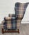 This is a vintage classic wingback armchair featuring a timeless plaid upholstery in muted blue, green, and burgundy...